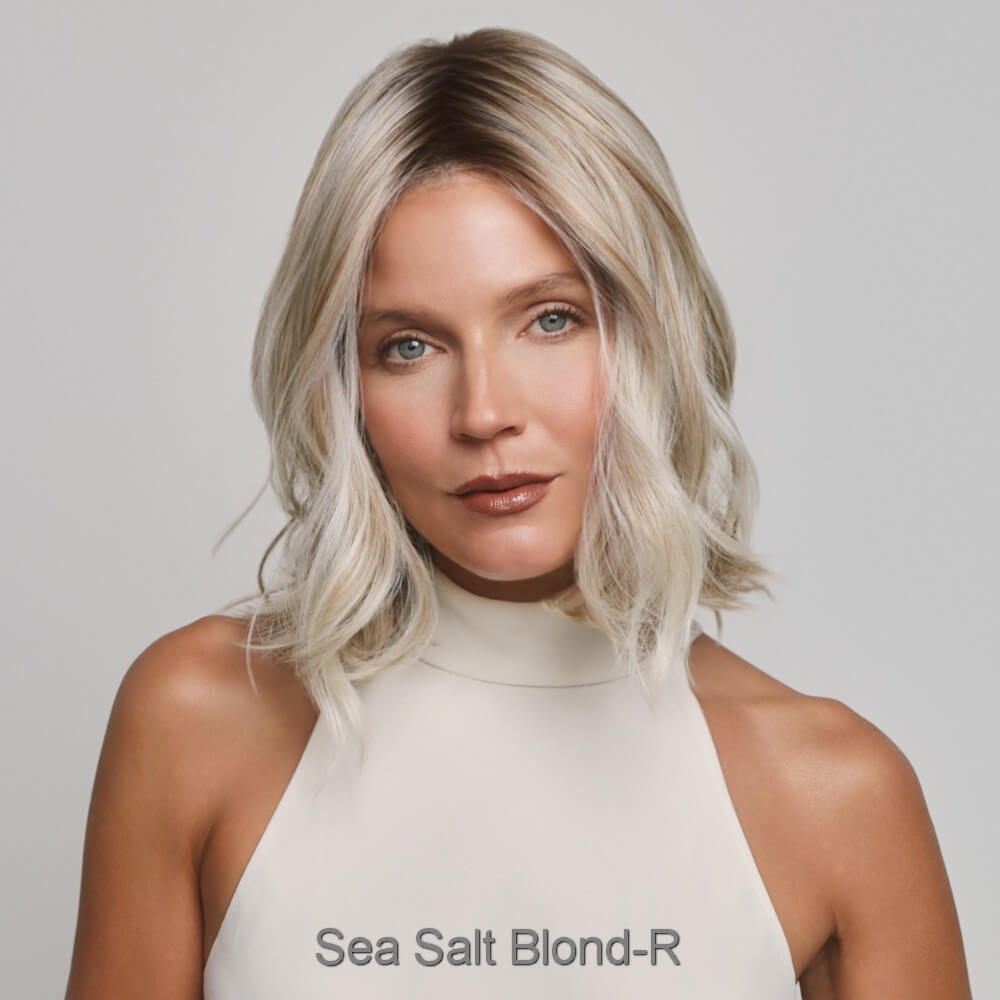 Yui  by Noriko wig in Sea Salt Blond-R. A shoulder-length wavy hair in a sea salt blonde color, wearing a cream-colored high-neck top against a light gray background. The text 'Sea Salt Blond-R' is printed at the bottom of the image.